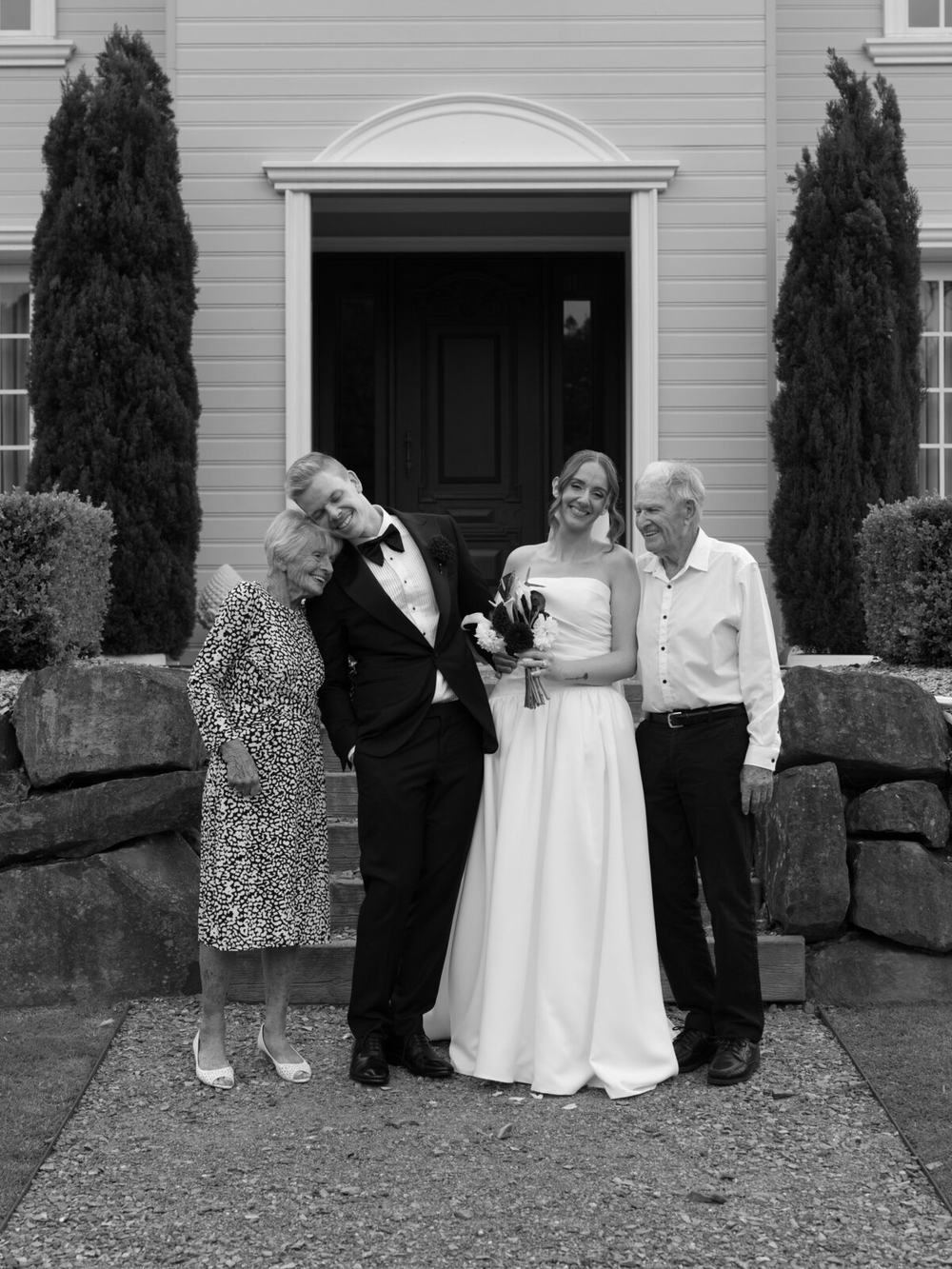 Couple with their parents at a doorway, black and white